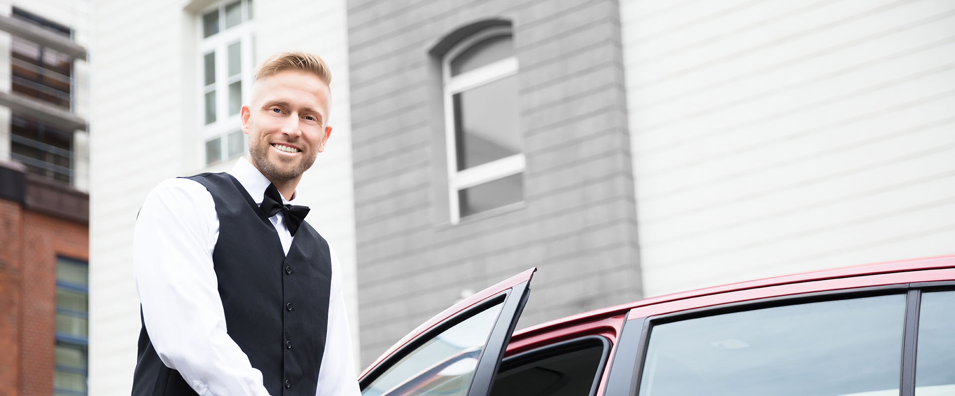 smiling valet opening a car door for his client